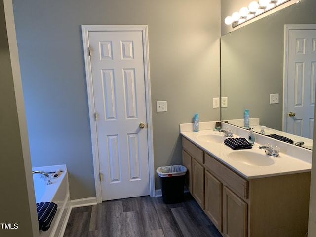 full bathroom with double vanity, a sink, a bath, and wood finished floors