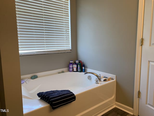 bathroom featuring baseboards and a bath