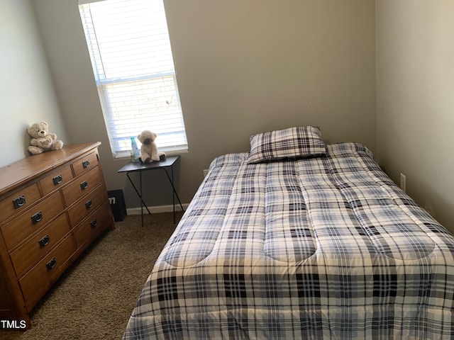 bedroom with dark carpet and baseboards