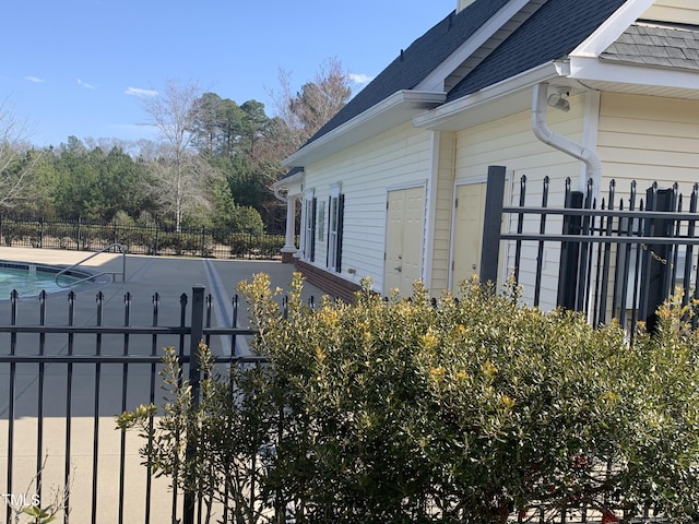 view of property exterior with a shingled roof, a fenced in pool, and fence