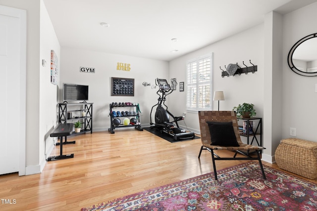 workout area with baseboards and wood finished floors