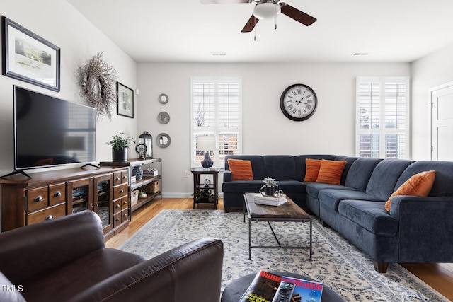 living area with visible vents, baseboards, light wood-style flooring, and a ceiling fan