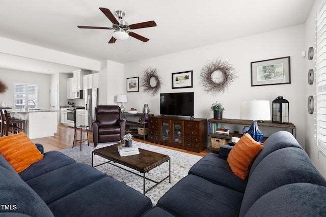 living room with a ceiling fan and light wood-type flooring