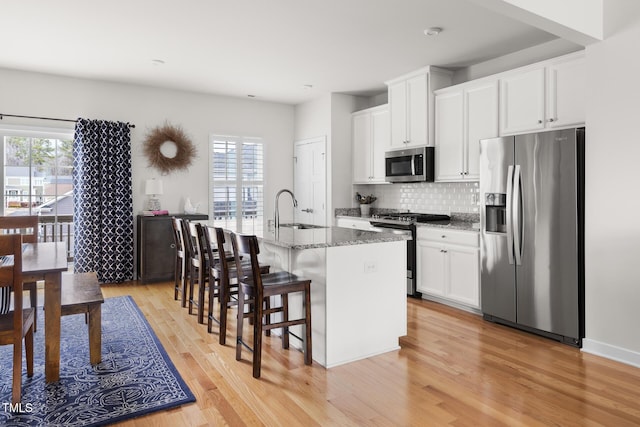 kitchen with a wealth of natural light, appliances with stainless steel finishes, an island with sink, and a sink