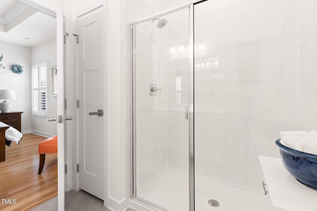 ensuite bathroom featuring a shower stall, wood finished floors, baseboards, and ensuite bathroom