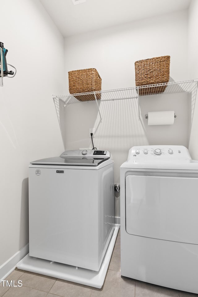 laundry area featuring laundry area, light tile patterned floors, washing machine and dryer, and baseboards