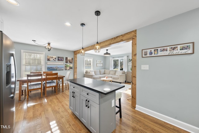 352 Leonard Rd, Louisburg, NC 27549 - kitchen with light wood-style flooring, stainless steel refrigerator with ice dispenser, decorative light fixtures, dark countertops, and a breakfast bar area