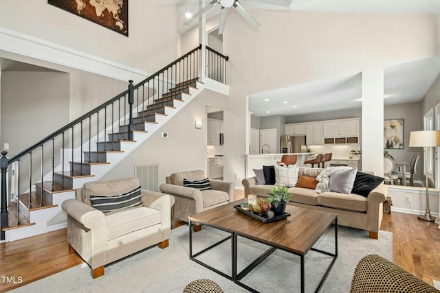 living area with recessed lighting, visible vents, light wood-style flooring, baseboards, and stairs