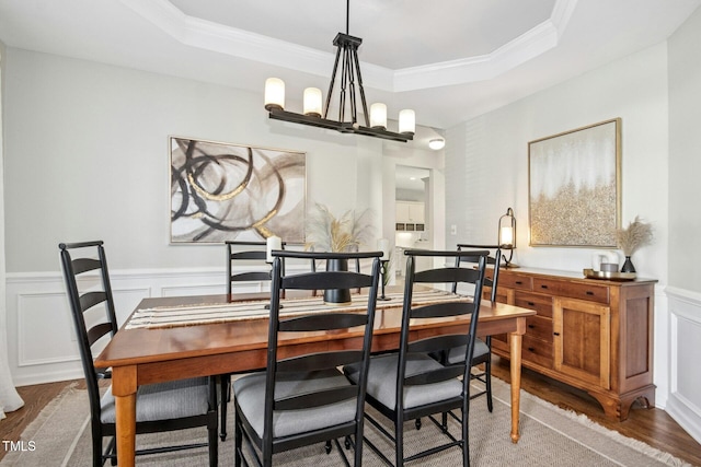 dining space with a chandelier, wood finished floors, and a raised ceiling