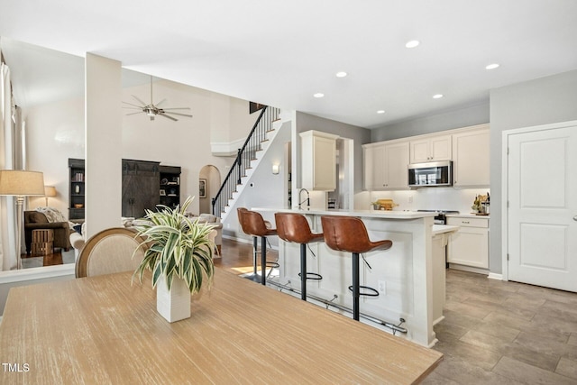 kitchen with open floor plan, light countertops, appliances with stainless steel finishes, and a kitchen breakfast bar