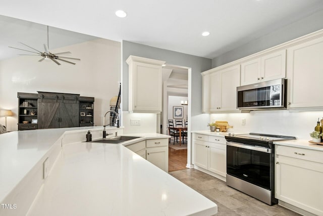 kitchen with ceiling fan, appliances with stainless steel finishes, light countertops, a sink, and recessed lighting