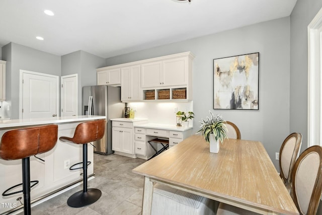 kitchen featuring a breakfast bar, white cabinetry, light countertops, and stainless steel fridge with ice dispenser