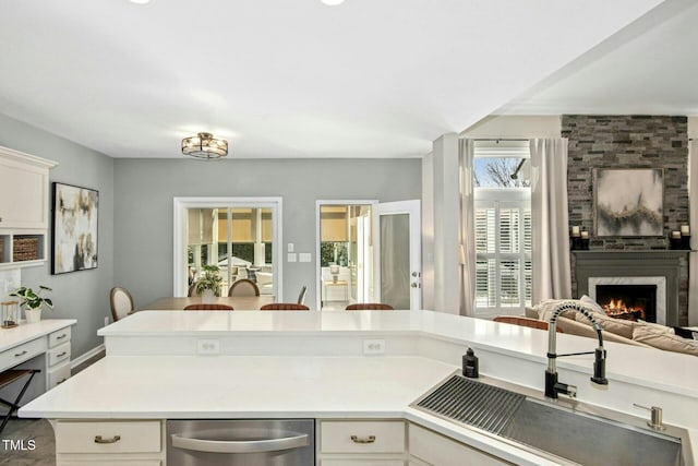 kitchen with a large fireplace, light countertops, a sink, and open floor plan