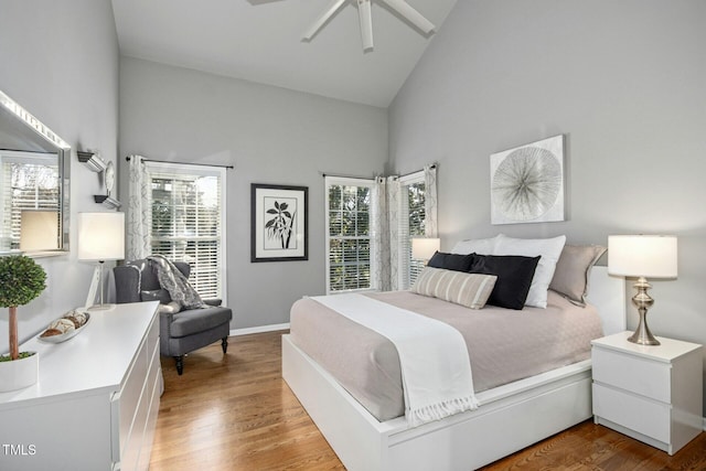 bedroom with high vaulted ceiling, ceiling fan, baseboards, and wood finished floors