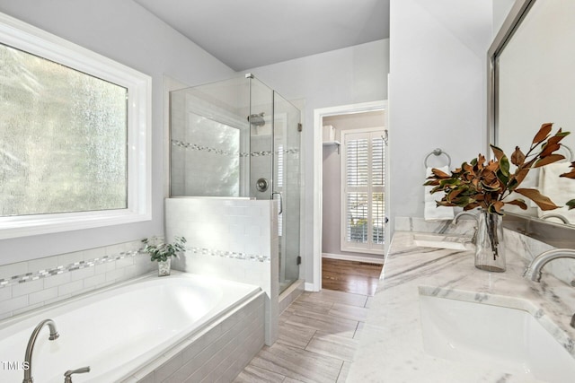 bathroom with a shower stall, a bath, and vanity