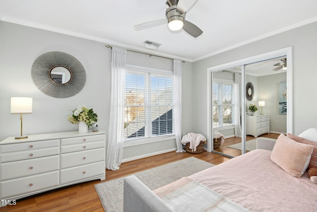 bedroom featuring crown molding, light wood finished floors, visible vents, a ceiling fan, and baseboards