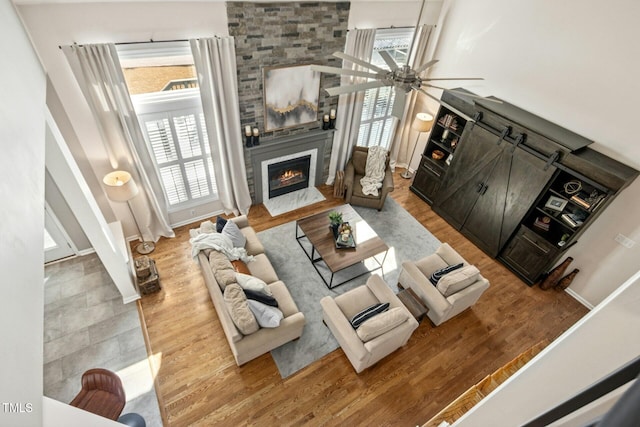 living area with a ceiling fan, a fireplace, baseboards, and wood finished floors