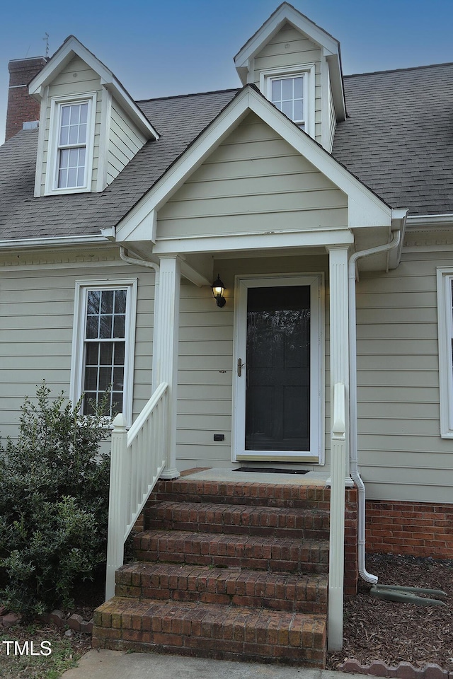 doorway to property featuring a shingled roof