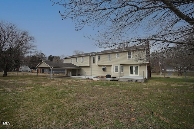 back of property with fence, a lawn, and a wooden deck