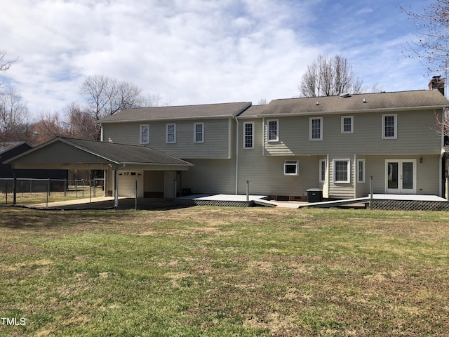 rear view of property featuring a garage, french doors, a lawn, and fence