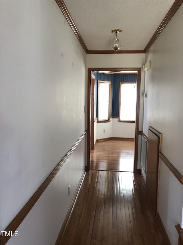 hall featuring ornamental molding, dark wood-style flooring, and baseboards