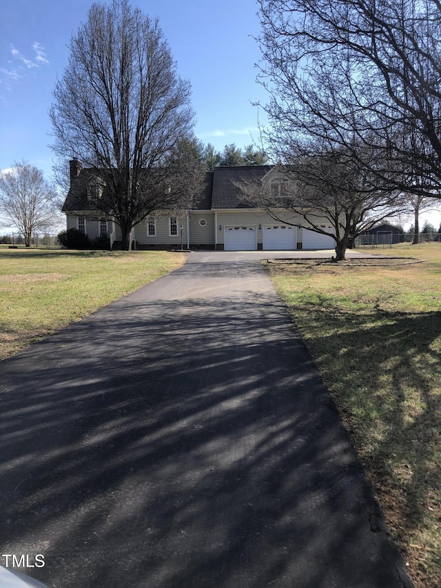 view of front of home with a garage, aphalt driveway, and a front yard