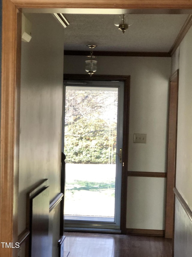 doorway with a wealth of natural light, crown molding, and wood finished floors