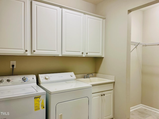 washroom with independent washer and dryer, a sink, cabinet space, and baseboards