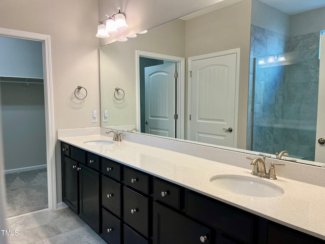 full bathroom with double vanity, tile patterned flooring, a walk in closet, and a sink