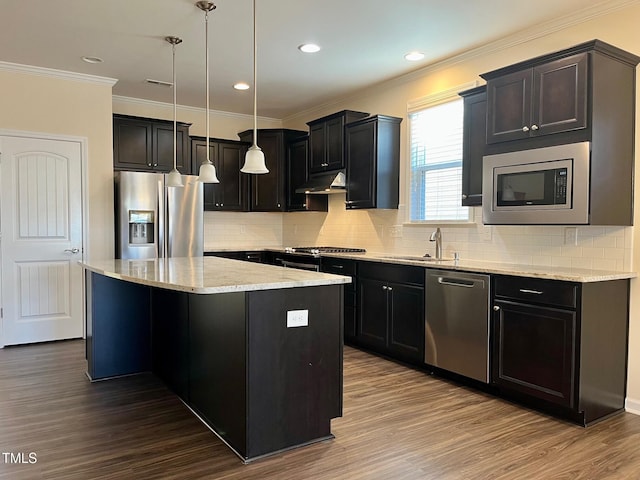 kitchen featuring light stone counters, stainless steel appliances, a sink, a kitchen island, and under cabinet range hood