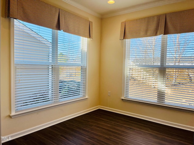 spare room featuring baseboards, dark wood-type flooring, plenty of natural light, and crown molding