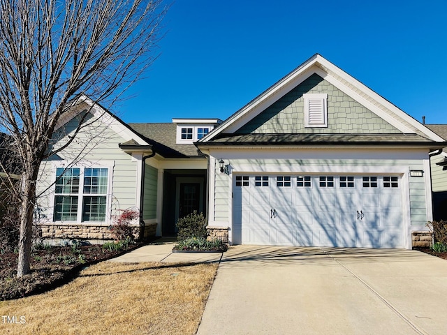 view of front of home featuring a garage, concrete driveway, and roof with shingles