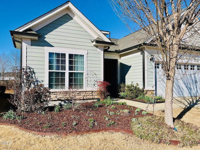 view of front of property featuring stone siding, concrete driveway, roof with shingles, and an attached garage