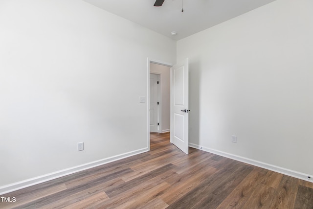 spare room with a ceiling fan, dark wood finished floors, and baseboards