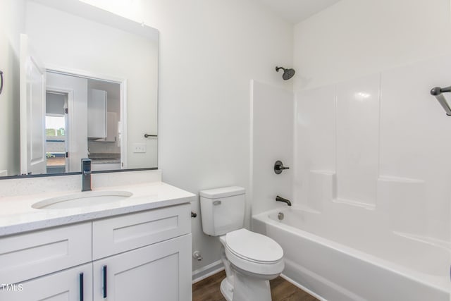 bathroom featuring toilet, wood finished floors, vanity, baseboards, and washtub / shower combination