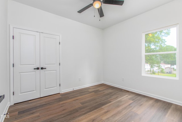 unfurnished bedroom featuring ceiling fan, dark wood-style flooring, visible vents, baseboards, and a closet