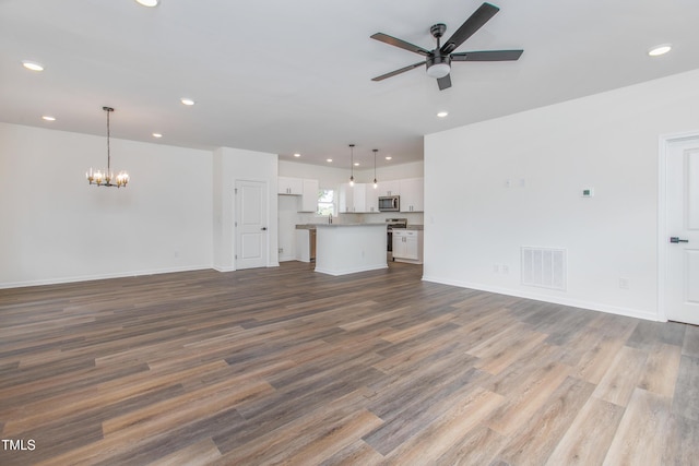 unfurnished living room featuring ceiling fan with notable chandelier, wood finished floors, visible vents, and recessed lighting