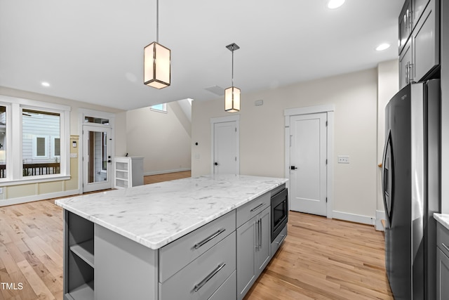 kitchen with light wood-style flooring, a kitchen island, freestanding refrigerator, gray cabinets, and black microwave