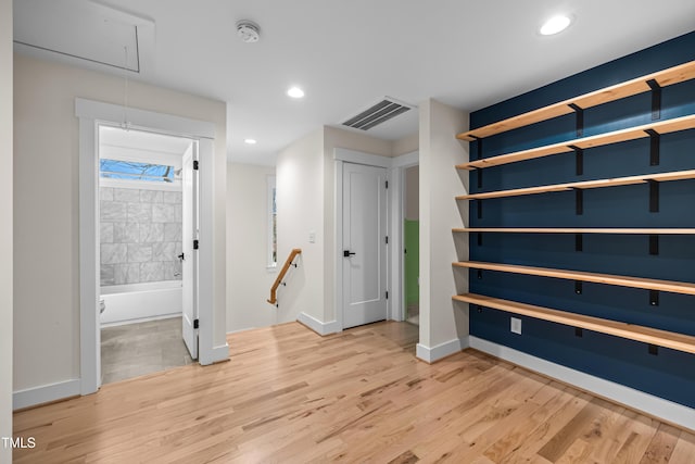 interior space featuring attic access, visible vents, light wood-style floors, and an upstairs landing