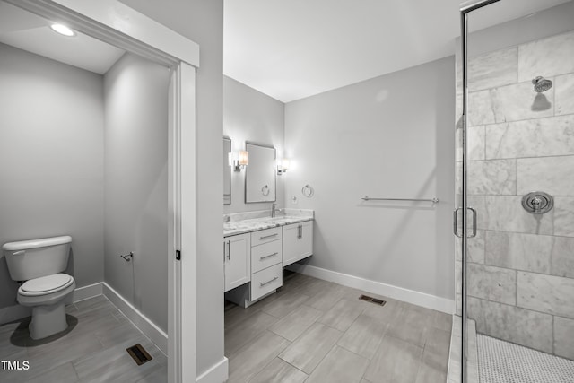 bathroom with toilet, vanity, visible vents, baseboards, and a stall shower