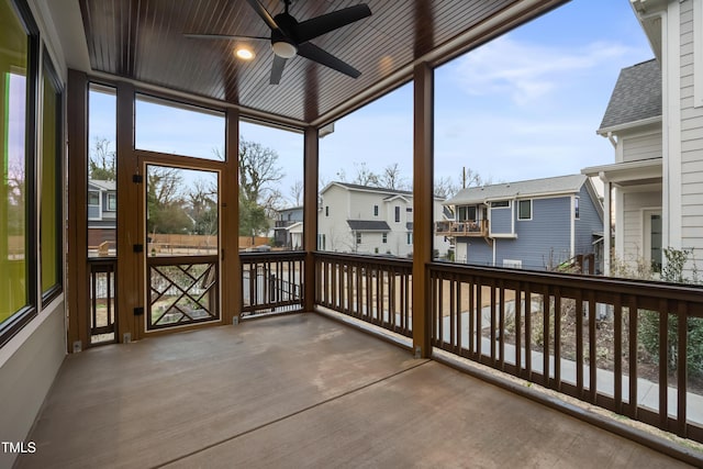 sunroom featuring a ceiling fan, a residential view, and wood ceiling