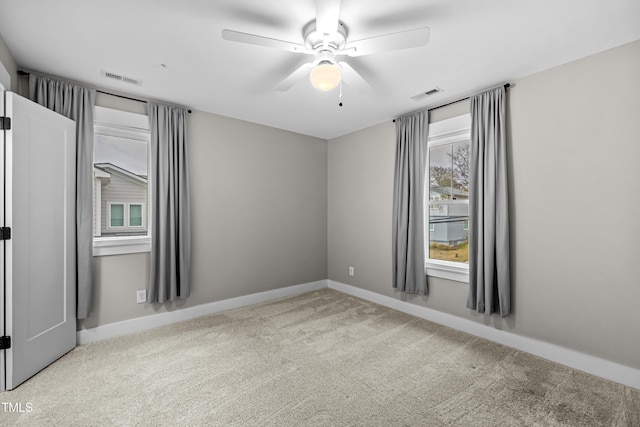 carpeted spare room featuring a ceiling fan, visible vents, and baseboards