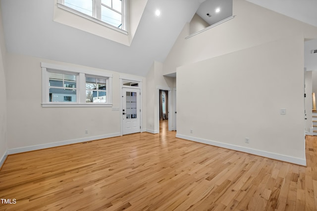 interior space with high vaulted ceiling, light wood-style flooring, and baseboards