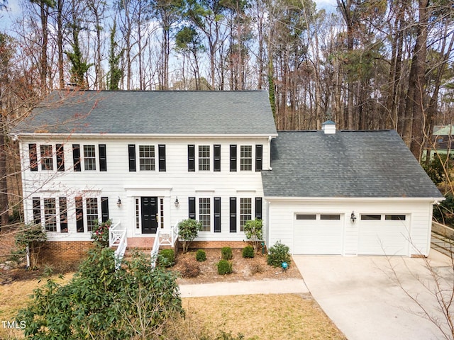 view of front of home with a garage, roof with shingles, concrete driveway, and a chimney