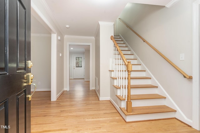 foyer entrance with stairway, crown molding, light wood-type flooring, and baseboards