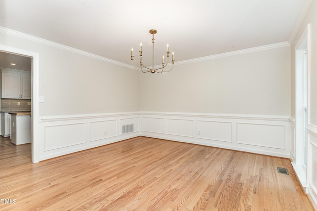 empty room featuring visible vents, crown molding, light wood-style floors, and an inviting chandelier