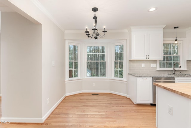 kitchen featuring light wood finished floors, a sink, white cabinets, dishwasher, and tasteful backsplash