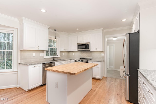 kitchen featuring a sink, appliances with stainless steel finishes, white cabinets, and butcher block counters