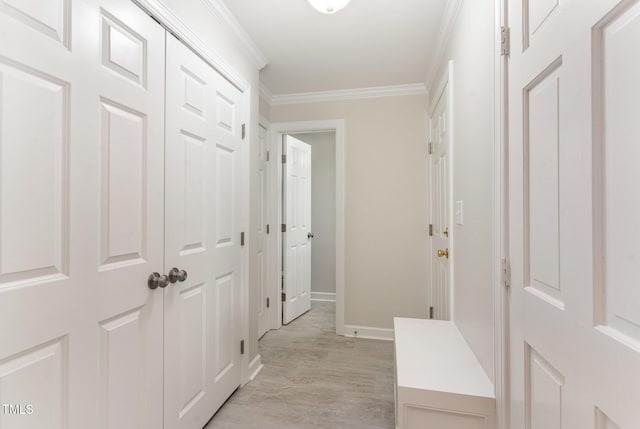 corridor featuring baseboards, ornamental molding, and light wood finished floors