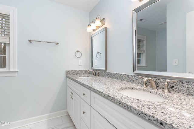 full bathroom with a sink, baseboards, marble finish floor, and double vanity